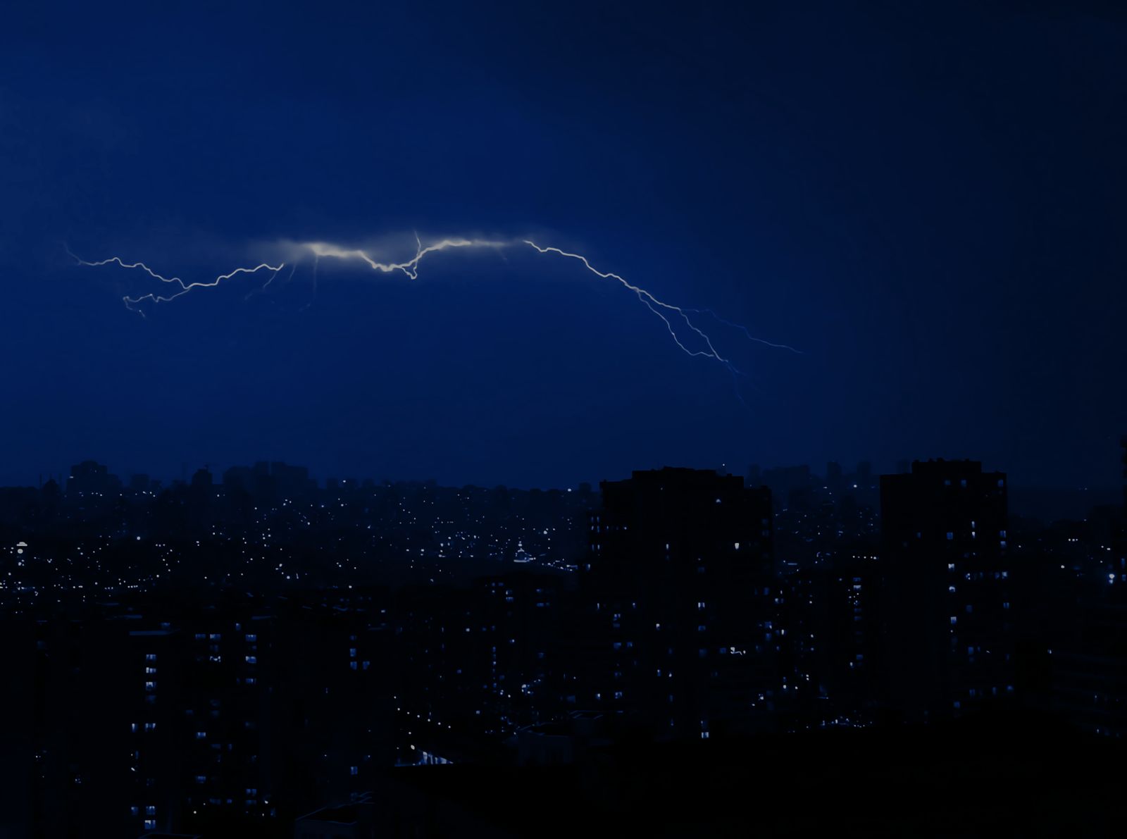 Lightning arcing over a dark city skyline at night