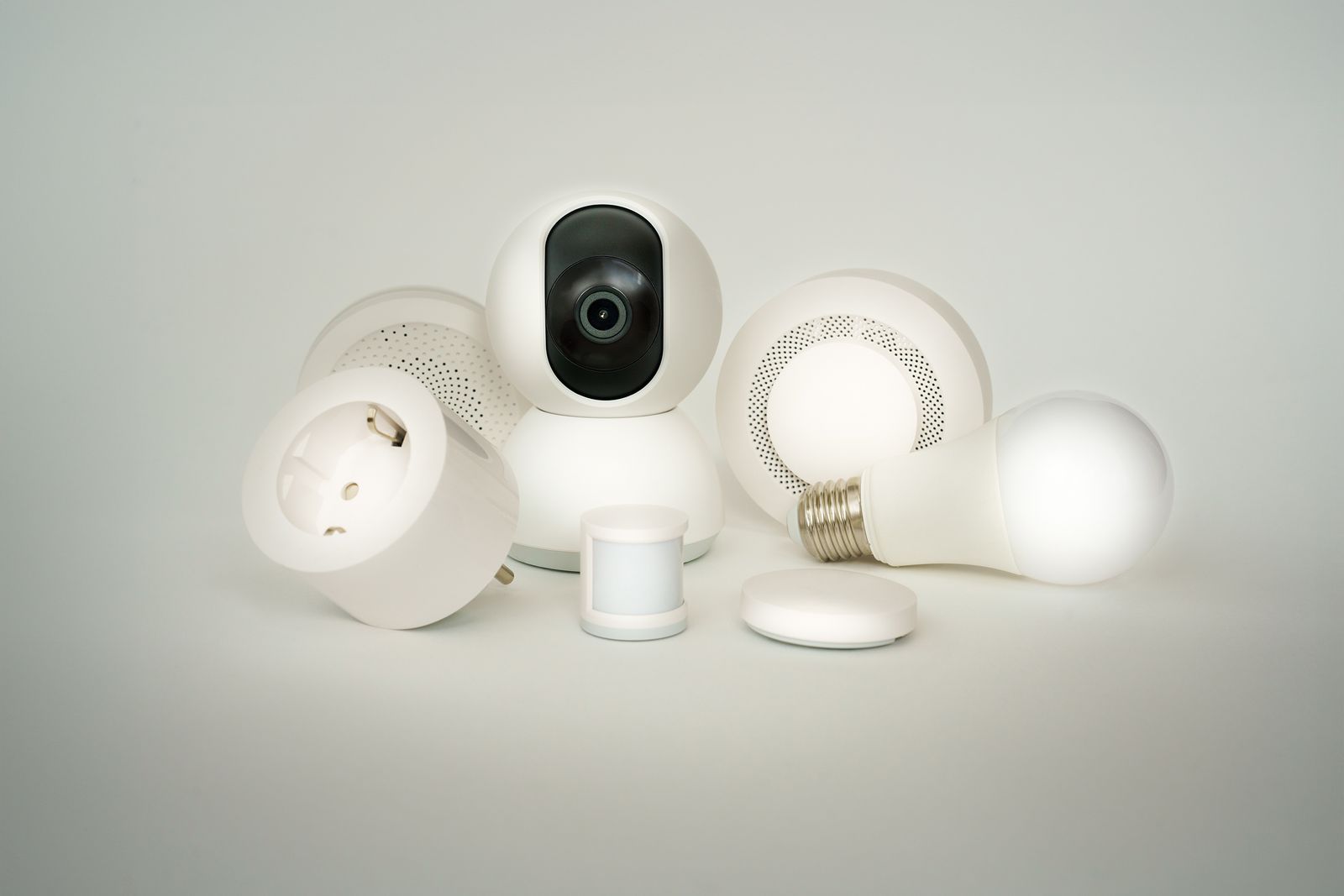 A collection of white smart home devices including sensors, a camera and a smart bulb
