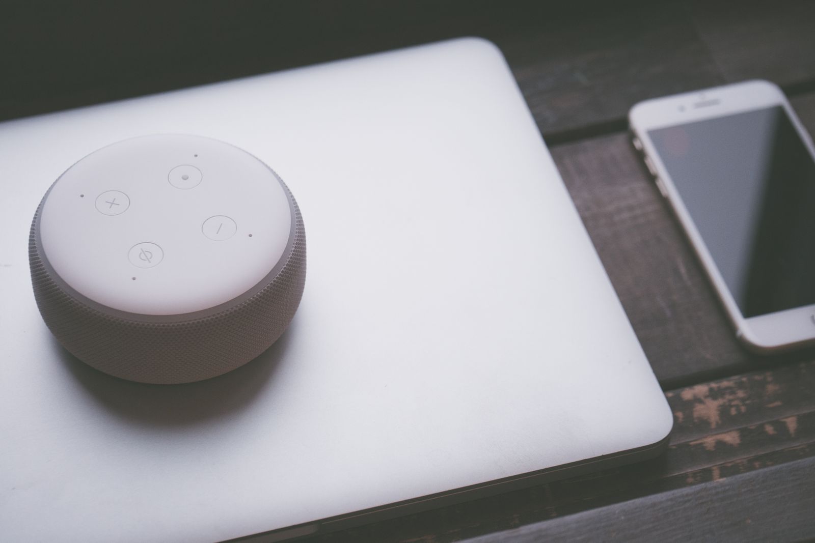 A smart speaker next to a smartphone on a desk