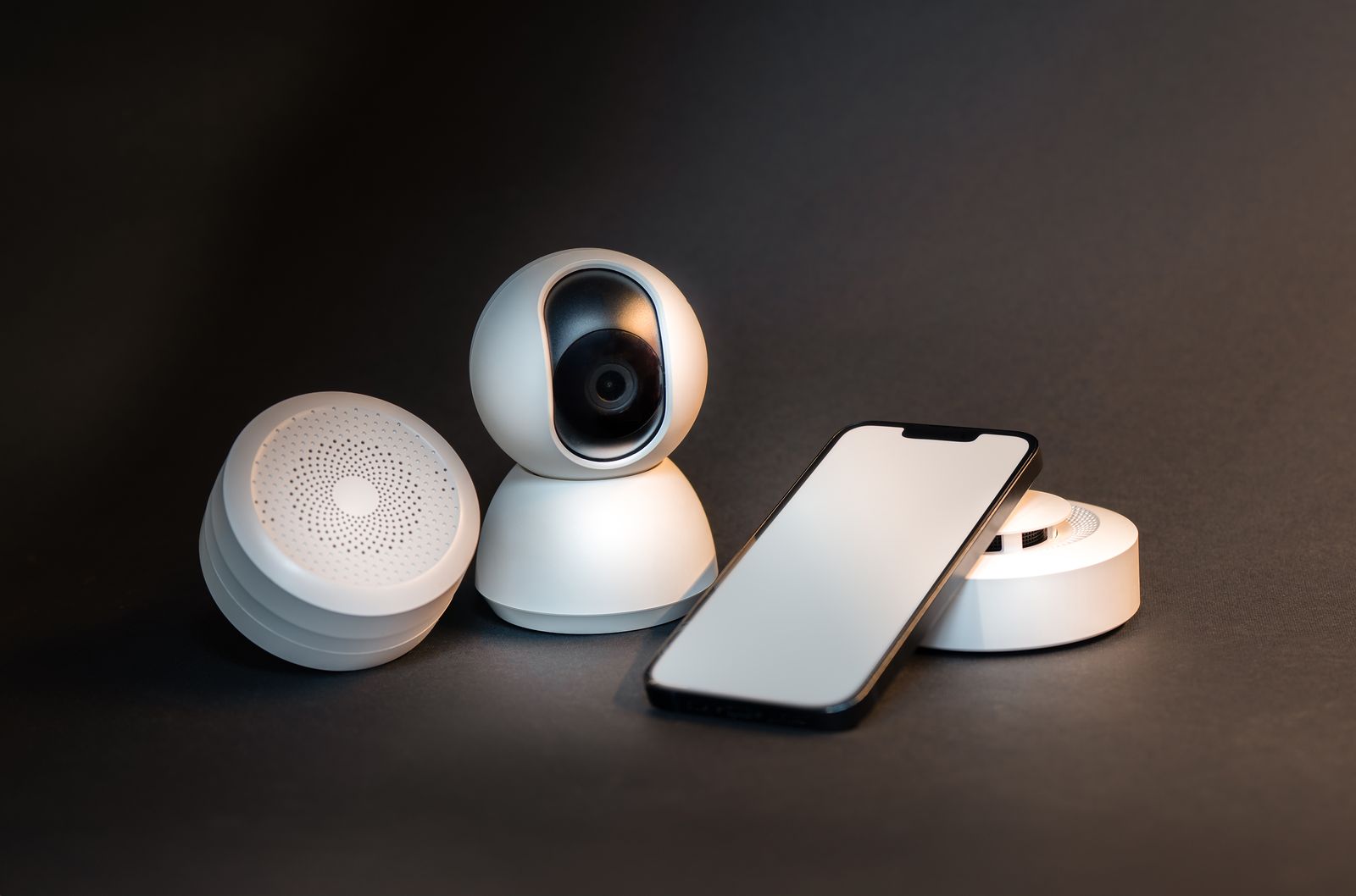 A motion sensor, a camera and a smartphone arranged on a dark background